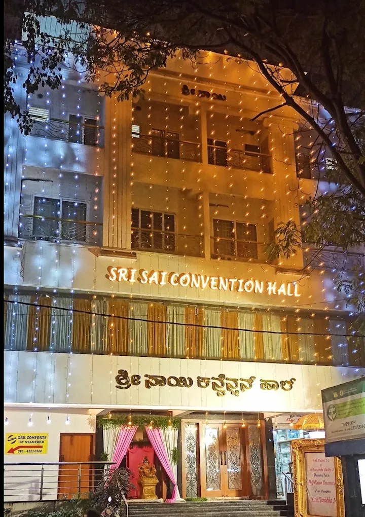 Sri Sai Convention Hall lit up at night, English and Kannada signage above the entrance