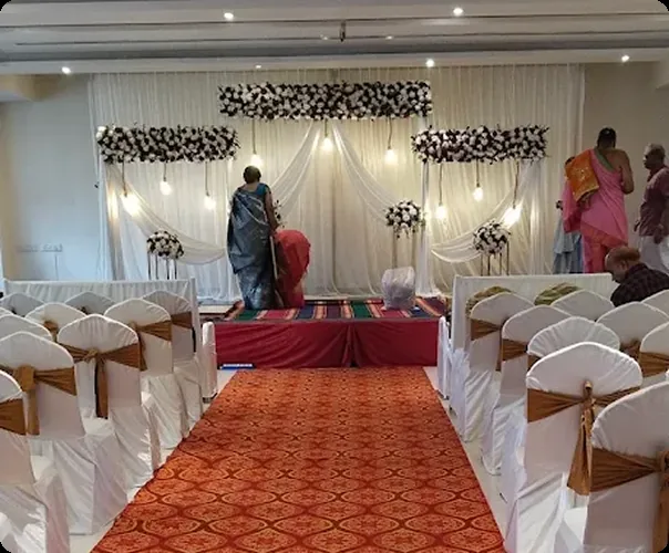 Guest seating either side of the red aisle, floral backdrop on stage