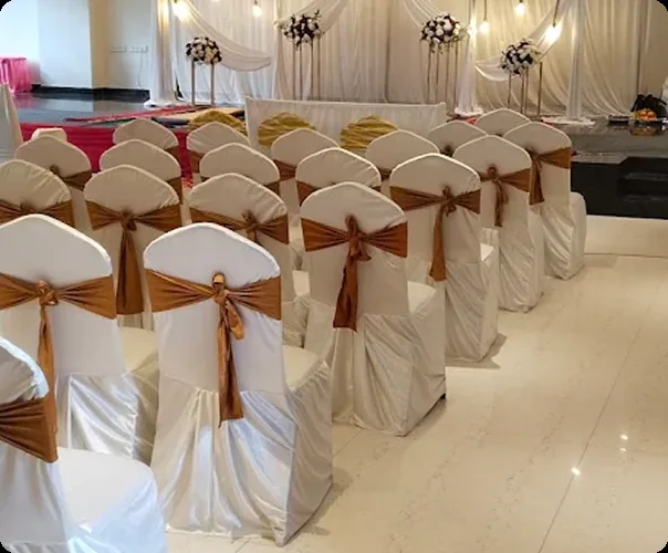Rows of banquet chairs in white covers with gold sashes