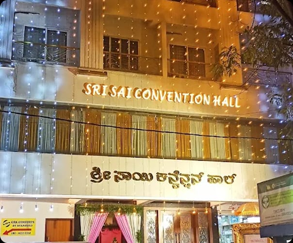 Sri Sai Convention Hall signage in English and Kannada lit at night, opposite Jayanagar 9th Block bus stop
