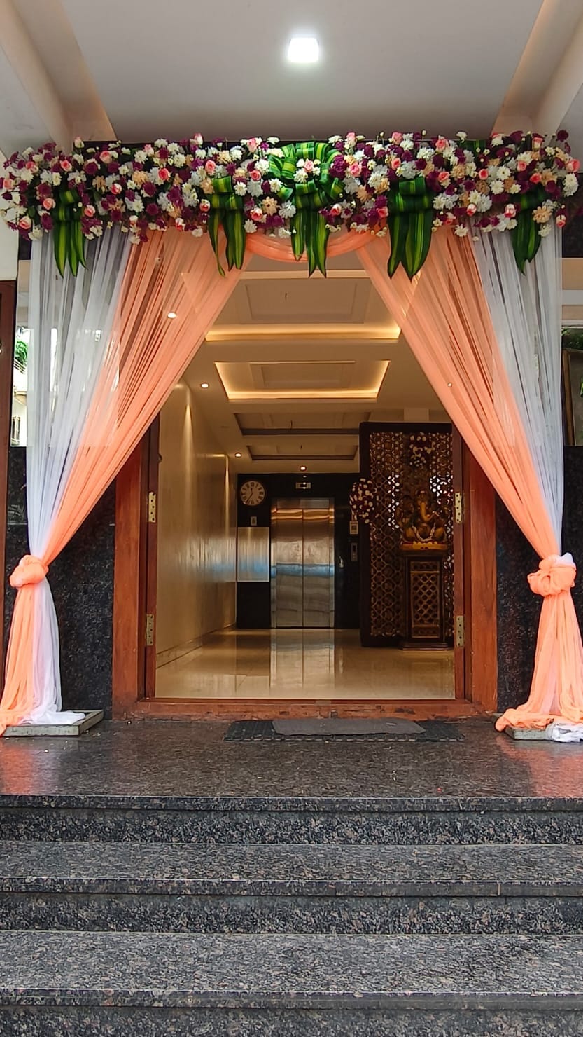 The entrance arch dressed with flowers, steps up into the lit foyer at Sri Sai Convention Hall, Jayanagar