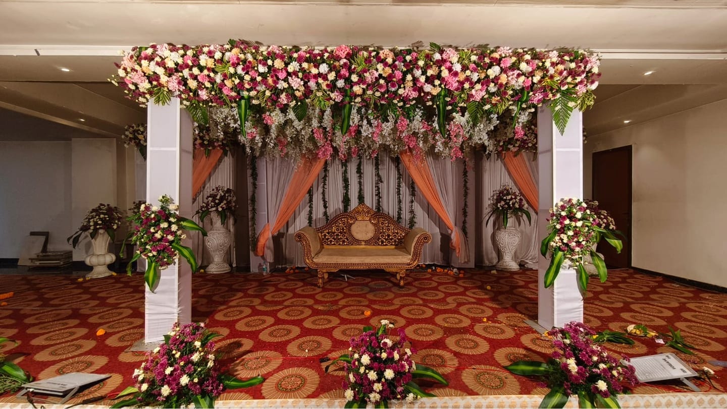 A reception stage with floral canopy and a carved settee, Sri Sai Convention Hall, Jayanagar 9th Block